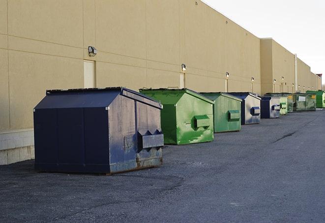 tilted front-load dumpsters being emptied by waste management workers in Creal Springs, IL